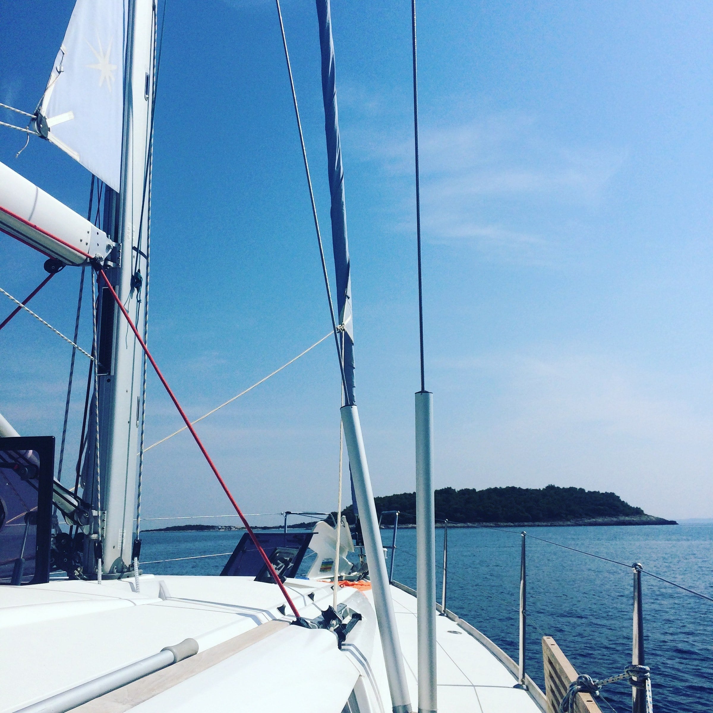 Bow of a sailing yacht approaching a quiet island