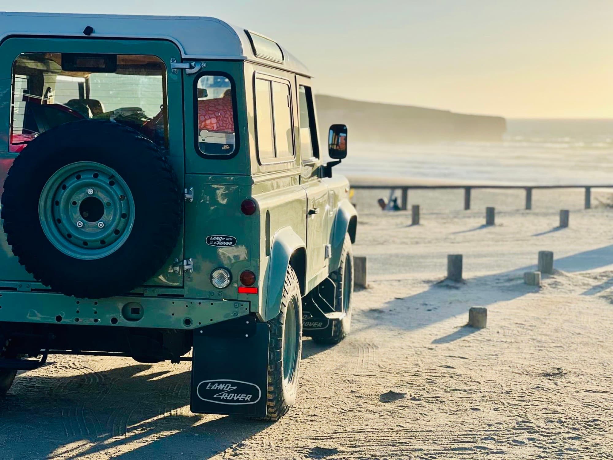 Land Rover Defender Heritage parked at the beach at golden hour
